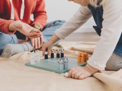 Ett barn och en vuxen spelar ett brädspel.