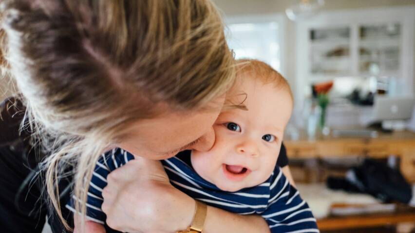 En mamma håller om en nöjd baby.
